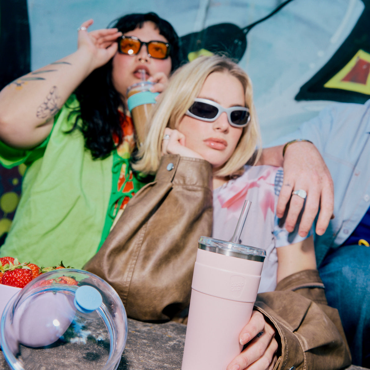 Two people sitting together with drinks and a colorful background