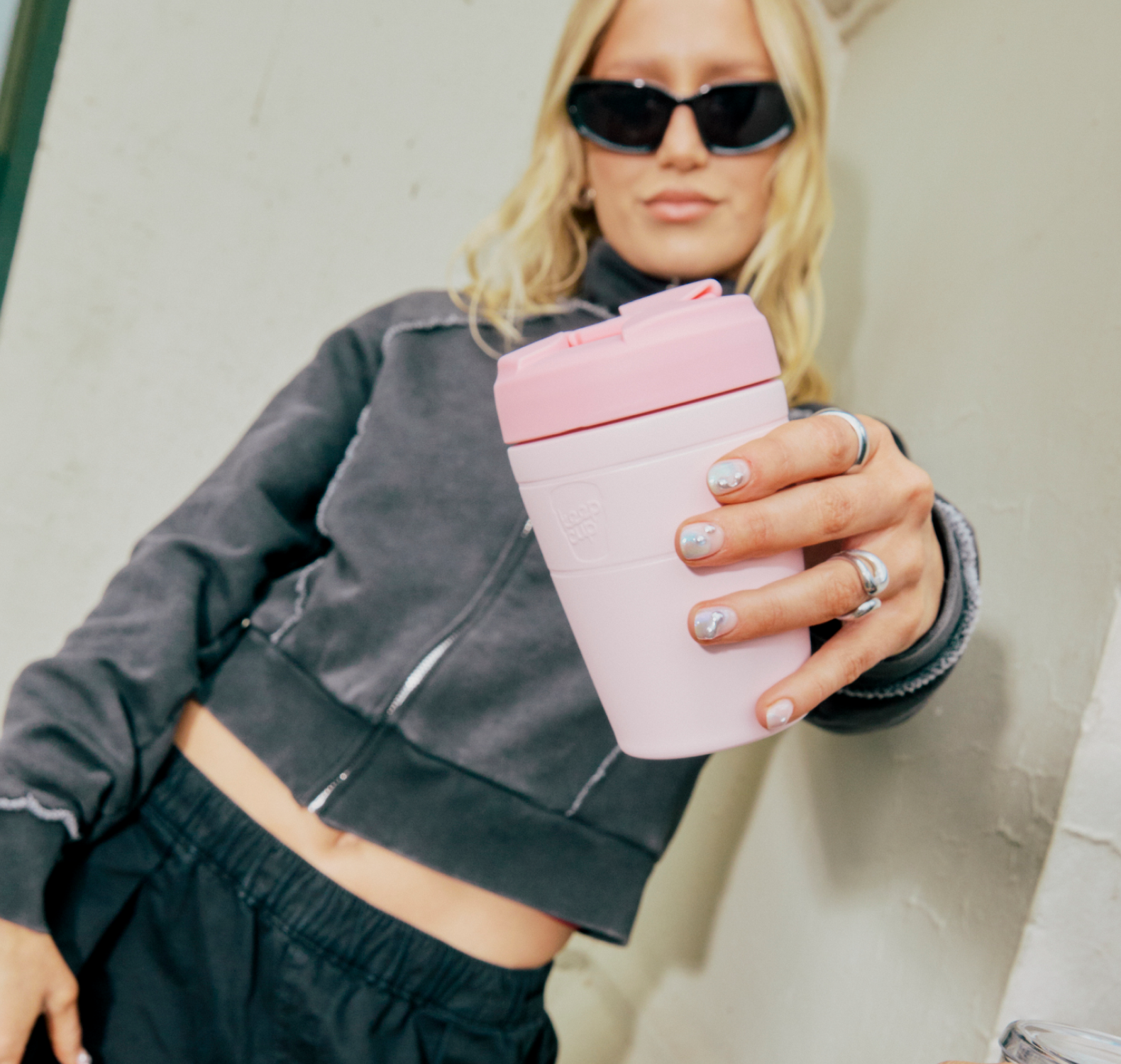 Woman in sunnies holding forward a Pashmak Pink KeepCup Travel mug