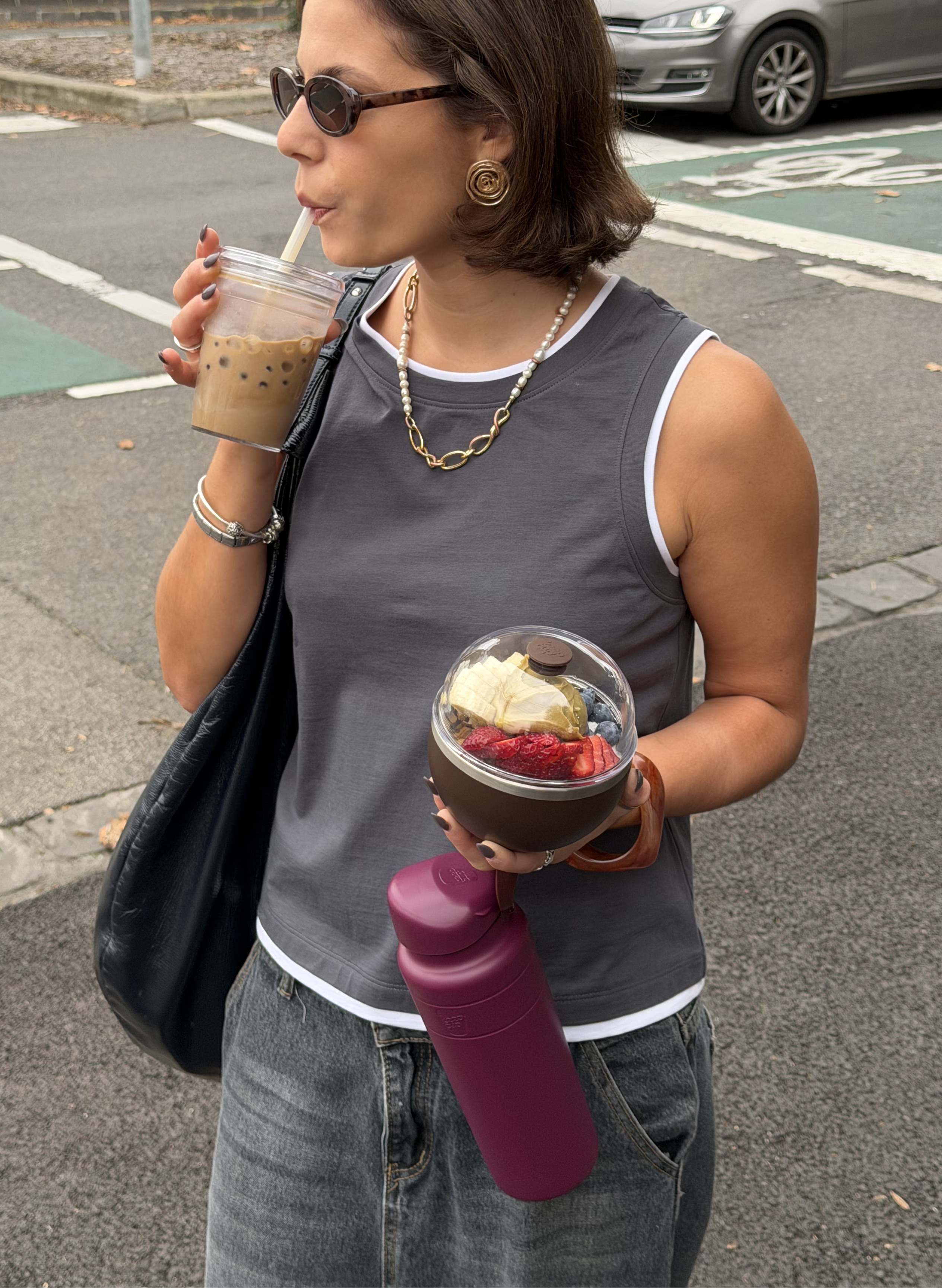 Cool woman in sunnies sipping boba from KeepCup Cold Cup with boba, carrying mulberry Ora Water Bottle and Go Bowl fuilled with acai.