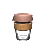 Glass reusable coffee cup with a cork sleeve and pink lid on a white background