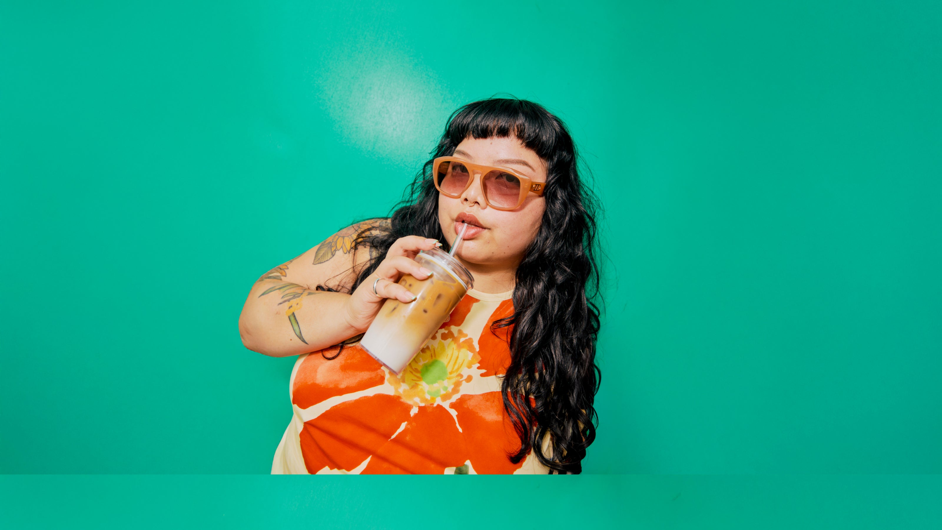 Person drinking from a straw against a teal background