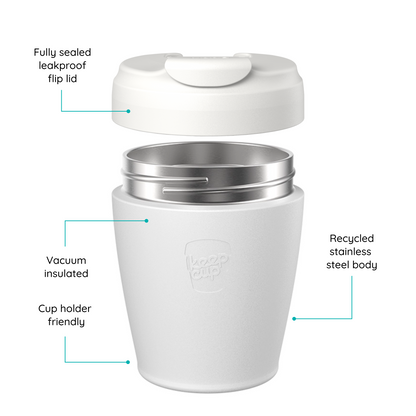 A reusable KeepCup travel cup shown on a white background with callout lines and text explaining features: fully sealed leakproof flip lid, vacuum insulated, recycled stainless steel body, and cup holder friendly. The cup is white with a stainless steel interior and a small embossed logo on the front.