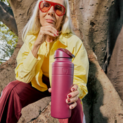 Person holding a mulberry water bottle outdoors
