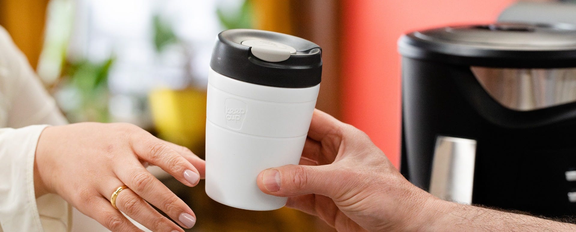 Woman holding KeepCup Traveller Buddies 12oz with coffee