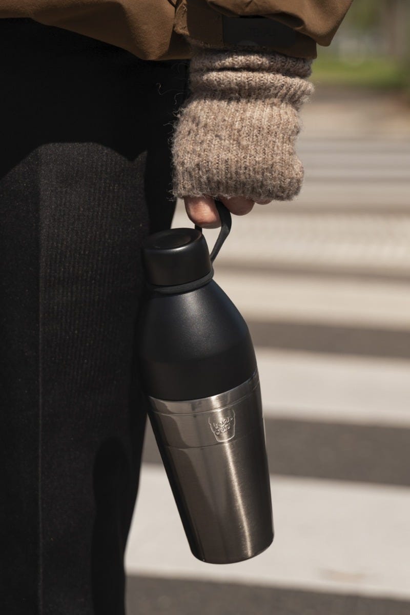 Person holding KeepCup Helix Bottle 16oz Nitro Black crossing the street