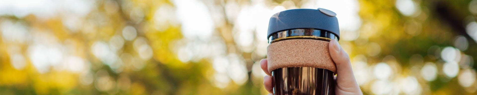 Woman holding up KeepCup Brew Cork cup in 12oz with black coffee