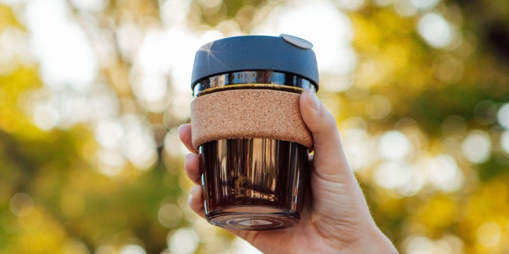 Woman holding up KeepCup Brew Cork cup in 12oz with black coffee